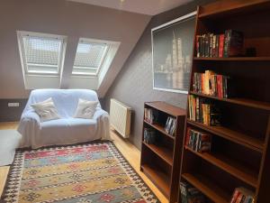 a room with a white chair and a book shelf at Balatonalmádi Pipacs Villa in Balatonalmádi