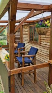 a wooden deck with chairs and a basket of flowers at Kōtare Cabin, Thames Coast in Tapu