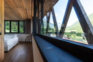 a bedroom with a bed and a window with mountains at Amus Suites Dolomites in Anterselva di Mezzo +29 photos