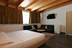 a bedroom with a bed and a couch and a tv at Hotel Mille Amici in Shëngjin