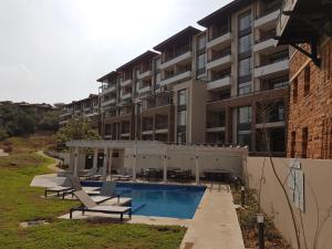 een appartementengebouw met een zwembad en twee ligstoelen bij Zimbali Suites 223 in Ballito