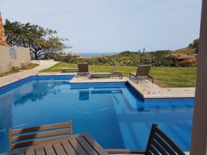 een zwembad met twee stoelen en een tafel bij Zimbali Suites 223 in Ballito