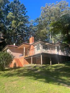 a large brick house with a porch on a lawn at Hoop Lodge in Bellingen