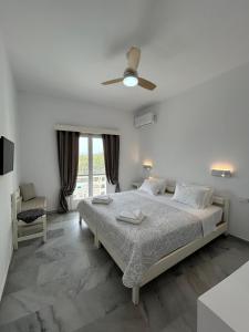 ein weißes Schlafzimmer mit Bett und Deckenventilator in der Unterkunft Hotel Zannet in Parikia