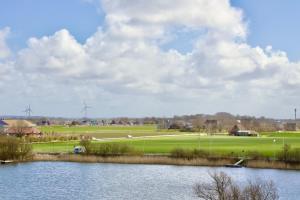 a view of a field with windmills and a lake at Meerblick 60 in Nordstrand
