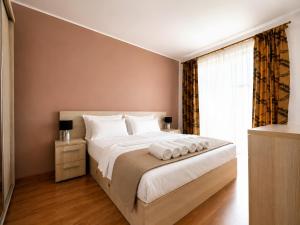 a bedroom with a large bed and a window at Brasov Altipiani Apartments in Braşov
