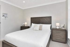 a white bedroom with a large bed and two night stands at Hunter Hideaway in Cessnock