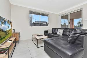 a living room with a leather couch and a tv at Hunter Hideaway in Cessnock