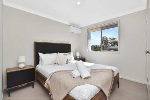 a white bedroom with a large bed and a window at Hunter Hideaway in Cessnock +10 photos