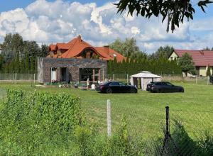 two cars parked in a field in front of a house at Gniazdo 35 in Okuninka