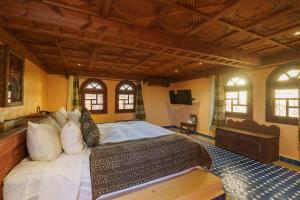 a bedroom with a large bed in a room with windows at Hotel Riad Xaluca in Merzouga