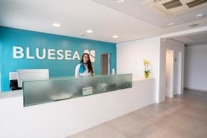 a woman standing behind a counter in a lobby at BLUESEA Playa Azul in Cala en Porter