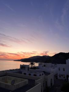a sunset over the ocean and white buildings at Bustan Shells House in Muscat