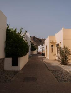 an empty alley with white buildings and a bush at Bustan Shells House in Muscat