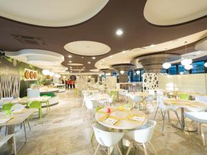 Meridiana Family & Nature Hotel في مارينا روميا: مطعم به طاولات وكراسي وأشخاص في الخلفية