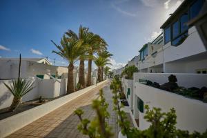 una calle con palmeras y edificios blancos en Villa Palmeras Beach Puerto del Carmen, en Puerto del Carmen