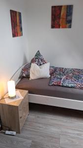 a bed with two pillows and a table with a lamp at Ferienwohnung Mariechen in Medebach