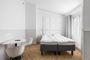 a white bedroom with a bed and a chair at Omena Hotel Turku Kauppiaskatu in Turku