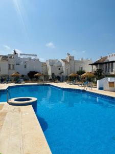 a large blue swimming pool with buildings in the background at Apartamento de las Buganvillas in Vera