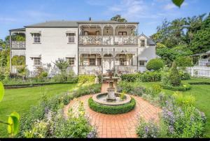 a large white house with a fountain in the yard at Middleton House Maleny in Witta