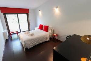 a bedroom with a white bed with red pillows at Casa de Freixo Casa de Freixo Refugio Tranquilo na Natureza in Ponte de Lima