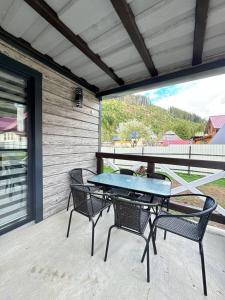 a patio with a table and chairs on a balcony at Котедж у Софійки in Synevyrsʼka Polyana