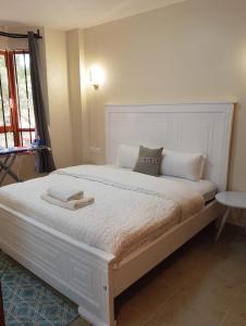 a bedroom with a large white bed with towels on it at MAIDA Apartment - SHAWMUT SUITES in Nakuru +11 photos