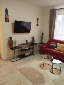 a living room with a red couch and a flat screen tv at MAIDA Apartment - SHAWMUT SUITES in Nakuru