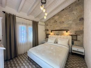 a bedroom with a white bed and a stone wall at Filizce Alaçatı in İzmir