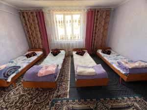 four beds in a room with a window at Temirbek Guest House in Jangy-Talap +2 photos