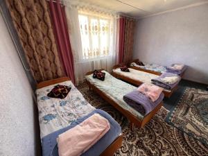 a group of three beds in a room at Temirbek Guest House in Jangy-Talap