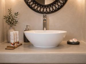 a white bowl sink on a counter with a mirror at Aenia Suites in Foinikiá +17 photos