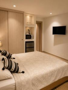 a bedroom with a large bed with a television on the wall at Aenia Suites in Foinikiá