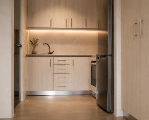 a kitchen with wooden cabinets and a stainless steel refrigerator at Aenia Suites in Foinikiá