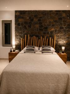 a large bed in a room with a brick wall at Aenia Suites in Foinikiá