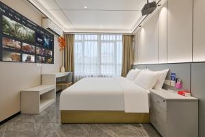 a bedroom with a large white bed and a desk at Four Seasons Clouds Xiamen North Railway Station Store in Xiamen