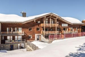 a log cabin in the snow with snow at Residence Le Roc Noir by Alpapart in La Rosière