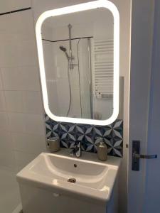 a bathroom with a white sink and a mirror at Vue Mer sur Juno Beach - Studio in Courseulles-sur-Mer