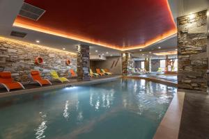 a swimming pool in a hotel with colorful chairs at Residence Le Roc Noir by Alpapart in La Rosière