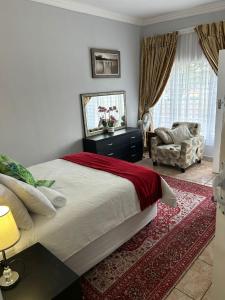 a bedroom with a large bed and a chair at The Family Room in Krugersdorp
