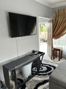 a living room with a table with a television on a wall at The Family Room in Krugersdorp