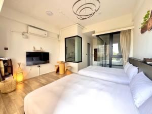 a bedroom with a large white bed and a tv at 安平胡桃民宿-免費停車-專屬電梯-公園景觀 #包棟可使用娛樂設施 in Tainan