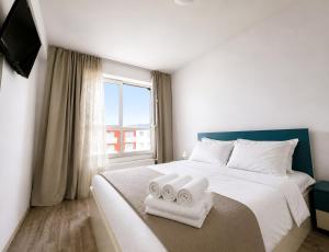 a bedroom with a large bed with towels on it at Brasov Altipiani Apartments in Braşov +30 photos