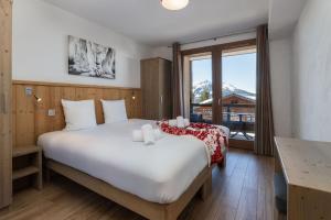 a bedroom with a large bed and a large window at Residence Le Roc Noir by Alpapart in La Rosière +75 photos
