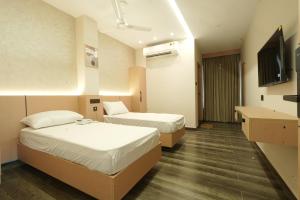 a hotel room with two beds and a television at Rest and Rise Inn in Bhīmavaram