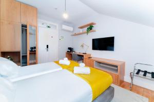 a bedroom with a large bed with a yellow blanket at A&S Suítes Coimbra in Coimbra