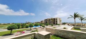 a view of a resort with palm trees and a building at Wateera Jebel Sifah-Beachfront & Golf View in As Sīfah