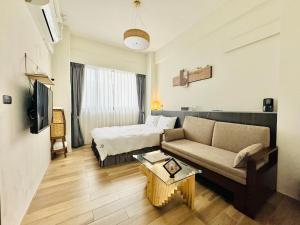 a hotel room with a couch and a bed at 安平胡桃民宿-免費停車-專屬電梯-公園景觀 #包棟可使用娛樂設施 in Tainan