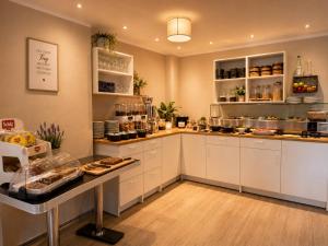 eine große Küche mit weißen Schränken und einer Arbeitsplatte in der Unterkunft Elbhotel Dresden by AURUM in Dresden