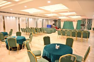 a banquet hall with green tables and chairs at Hotel Velvet The Ultimate in Prayagraj
